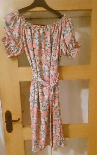 A customer's lovely summer dress made from the pink and white floral crepe fabric, hanging on a door.