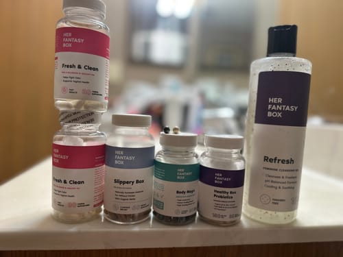 Reviewer's collection of Her Fantasy Box products, including supplements and cleansing gel, on a counter.