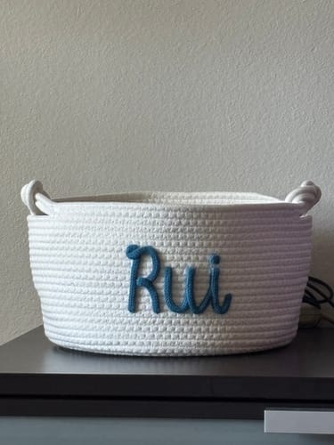 Customer's personalized white knitted basket with the name 'Rui' in blue yarn on the front.