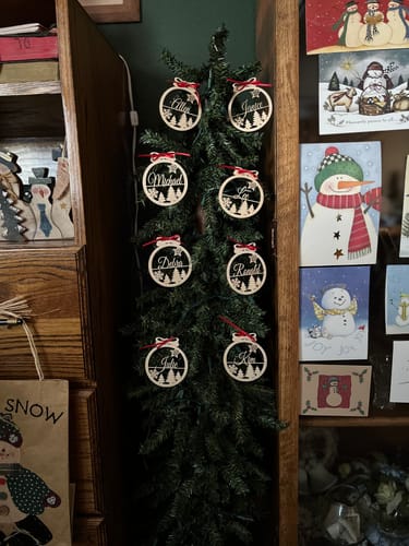 Customer's personalized wooden ornaments with names displayed on a memory tree.