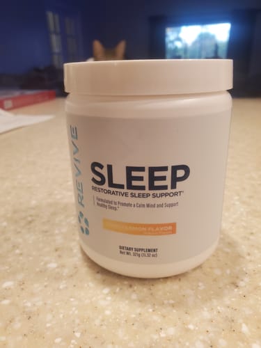 Customer's white tub of Revive Sleep supplement in Peach Lemon flavor, shown sitting on a countertop.