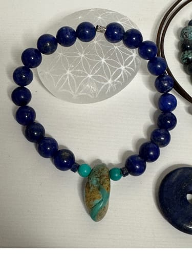 Gros plan du bracelet en lapis-lazuli d'un client, personnalisé avec des perles de turquoise sur un support blanc.