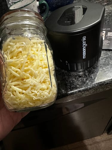 Customer's black Mason Genie Vacuum Sealer on a counter next to a mason jar filled with shredded cheese.