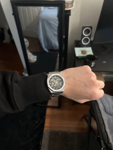 Reviewer wearing a silver-colored skeleton watch with an octagonal bezel.