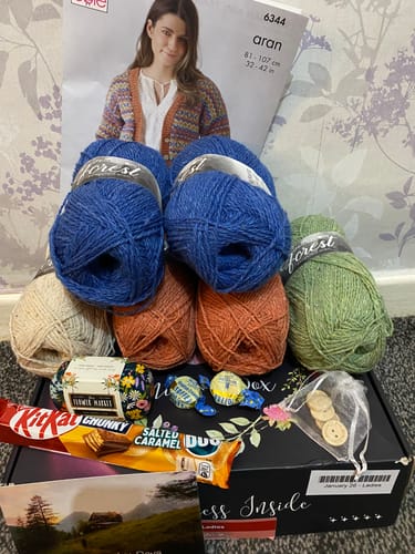 Customer's January Ladies Box showing colorful yarn, a knitting pattern, and some small treats.