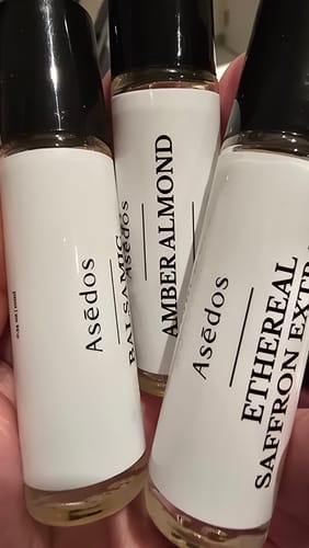 Customer holding three travel-size roll-on perfume oil bottles.