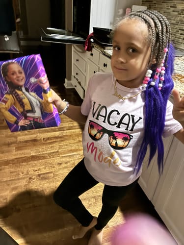Reviewer's child smiling while holding a custom 'K-Pop Queen' canvas with their photo on it.