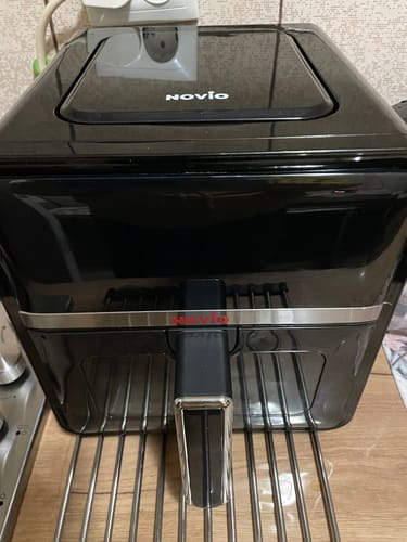 Recenzentul arată friteuza cu aer cald închisă, care conține tava de protecție din silicon.