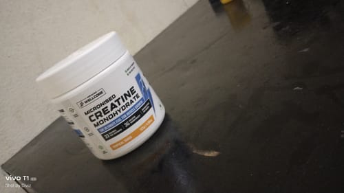 Customer's white tub of Wellcore Creatine Monohydrate in Tropical Tango flavor on a dark surface.