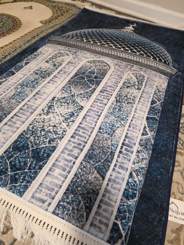A reviewer's Crystal Dome Padded Prayer Mat in dark blue, featuring an elegant mosque design on the floor.