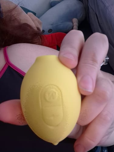 Close-up of a reviewer holding the yellow Lem Clitoral Massager in their hand, showing the controls.