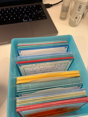La FLASHBOX bleue pastel d'un client, remplie de nombreuses fiches de révision colorées sur un bureau.