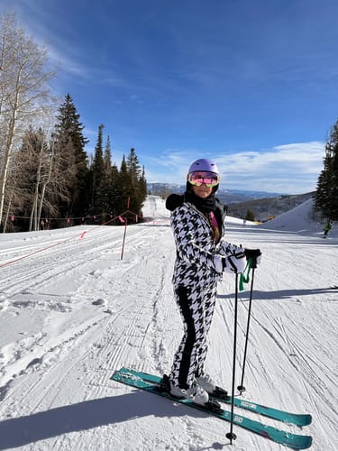 Reviewer posing on a snowy slope in the slim fit ski pants, part of a black and white houndstooth suit.