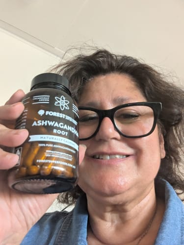 Reviewer smiling while holding a bottle of Organic Ashwagandha Capsules.