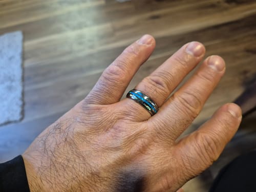 A customer's hand wearing the Vanguard ring, showcasing its vibrant blue opal and abalone inlay.