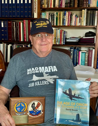 Reviewer proudly wears the grey Naval Aircrewman shirt while holding a P-3 Orion book and plaque.