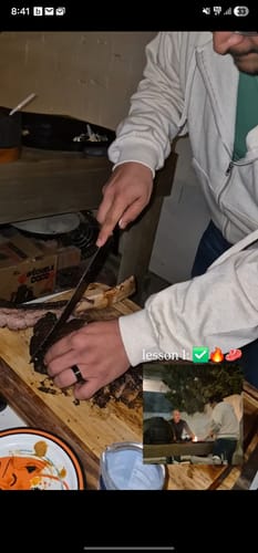 Un cliente cortando un filete Rib Eye Tomahawk cocido sobre una tabla de madera.
