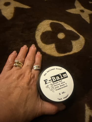 Reviewer holding a 2 oz. tin of F-Balm, showing the effect of the balm on their hand.
