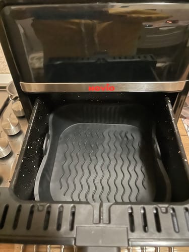 Clientul arată tava de protecție din silicon goală, așezată în interiorul unei friteuze cu aer cald.