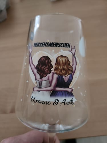 Ein Kunde hält das personalisierte Leonardo Puccini Weinglas mit dem Aufdruck „Herzensmenschen“ und zwei Namen.