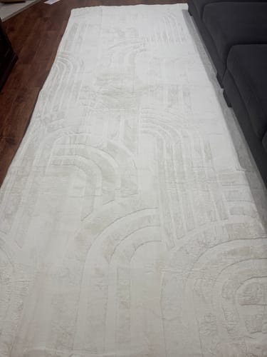 Customer's cream Mellow Mat showing its soft, carved geometric pattern on a dark wood floor.