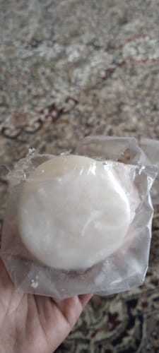 Customer holding the round, white HAIR REVIVER solid shampoo bar in its clear packaging.