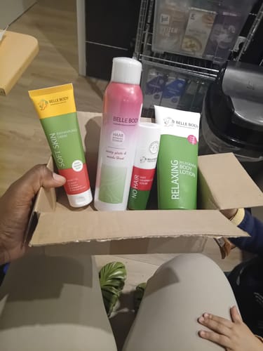 Ein Rezensent hält das Probier Set mit vier Produkten in der geöffneten Schachtel auf dem Schoß.