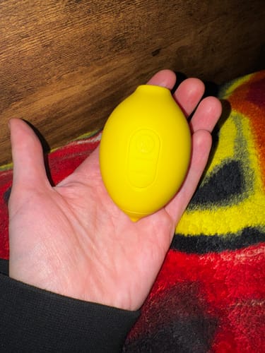 Customer holding the yellow Lem Clitoral Massager in the palm of their hand.