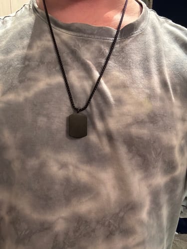 Customer wearing the black Matte Urn Dog Tag necklace against a tie-dye shirt.