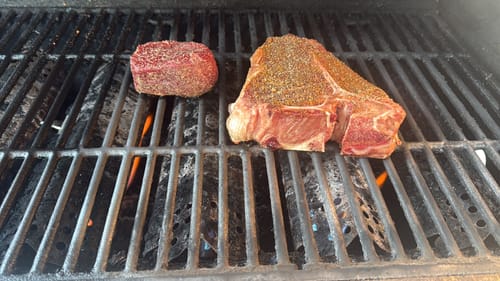 Customer's seasoned Porterhouse Steak and a filet mignon on a hot grill.