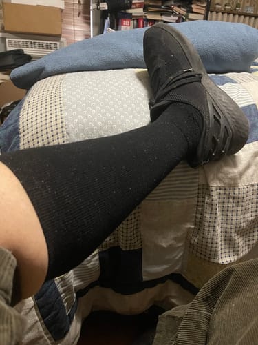Customer wearing a black Performance Eucalyptus Compression Sock on their lower leg indoors.