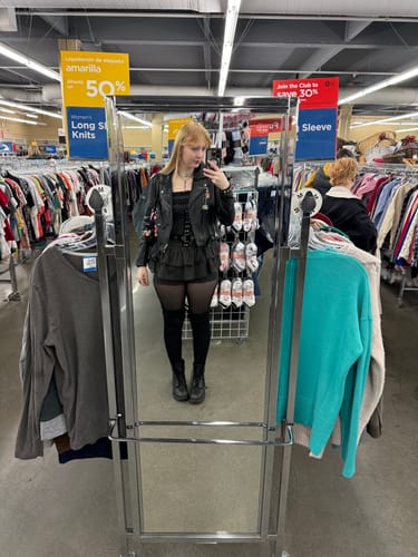 Reviewer taking a mirror selfie in a store wearing the Grunge Doll Stripes Flared Romper Dress, styled with a black jacket and boots.