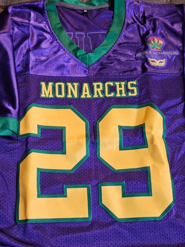 Customer's custom football jersey in purple, gold, and green, showing 'MONARCHS' and the number '29' stitched on the front.