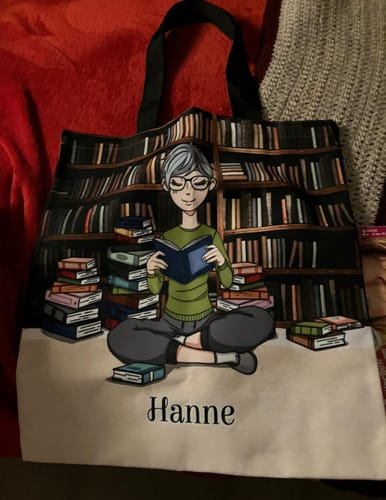 Rezensent zeigt eine personalisierte Stofftasche mit der Illustration einer lesenden Person und dem Namen 'Hanne'.