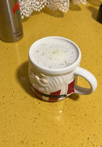 Reseñador muestra su espumoso Té Matcha Premium en una taza de Papá Noel.