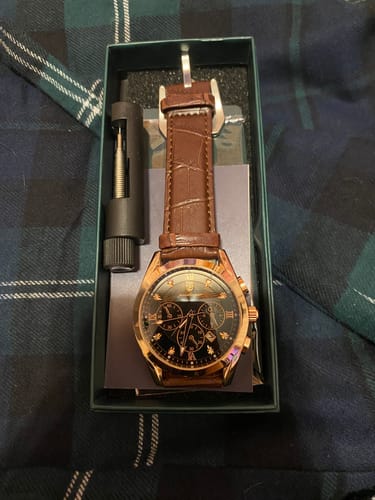 Customer's gold Lucky Fours® Voyager watch with a brown leather band, displayed in its packaging with an adjustment tool.