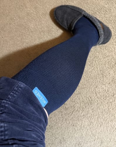 Customer wearing a dark blue Performance Eucalyptus Compression Sock, showing the ribbed fabric and 'Hushed' tag.