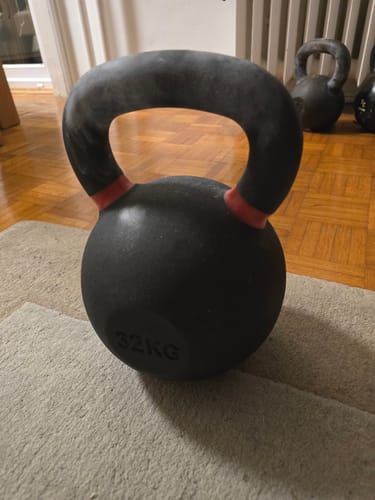 Customer's black 32kg Strength Shop cast iron kettlebell with red handle markings, sitting on a rug.