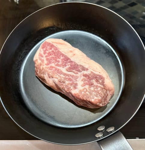 Reviewer's raw Tri-Tip Steak in a dark pan, showing its marbling before cooking.