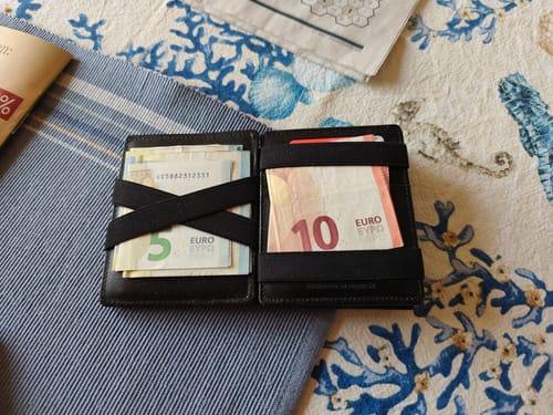Customer's open black Flap Boy magic wallet showing the elastic straps holding Euro banknotes.