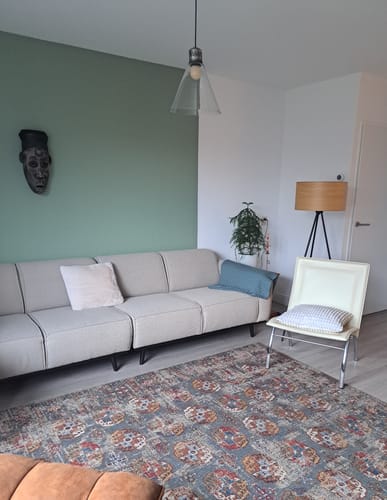 Klant toont het Kasak Vloerkleed met een doorleefd patroon in een woonkamer.