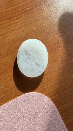 La pierre anti-stress Cristal de Roche d'un client, une pierre blanche et lisse posée sur une table en bois.