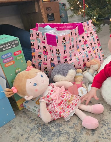 Customer's soft Leyadoll on the floor with other gifts. The gold personalization on the doll's patterned dress is hard to see.