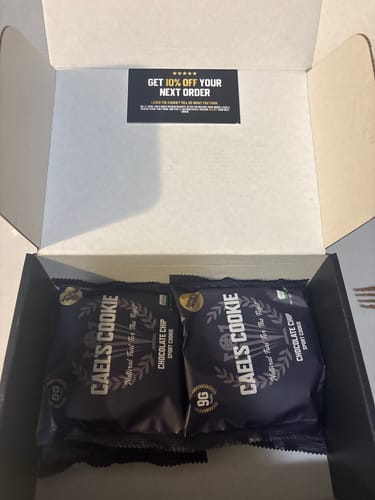 Customer's open shipping box with two packaged Cael's Chocolate Chip Cookies.