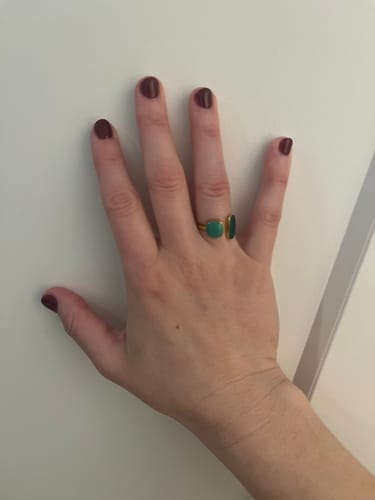 Customer's hand wearing the Green Willow Wrap Ring with two emerald-green stones.