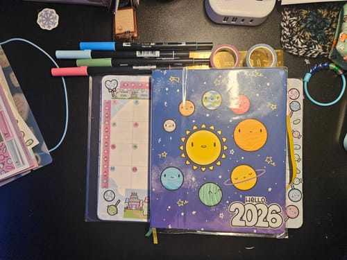 Reviewer's planner supplies including the 'Hello 2026' sticker from the Calendars Sticker Set on a notebook.