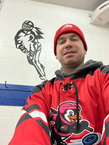 Customer wearing a custom red and black hockey jersey with a lace-up neck and a penguin logo.