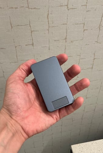 Customer holding the closed, gray Mission Case in their hand against a textured wall.