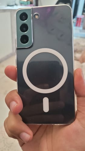 Reviewer holding a Samsung Galaxy S22 in the clear Magsafe case, showing the white magnetic ring on the back.