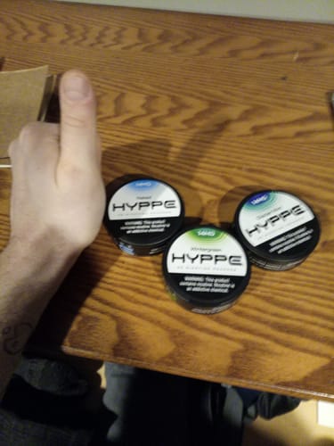 Customer gives a thumbs-up next to three cans from their HYPPE Sample Pack on a wooden table.